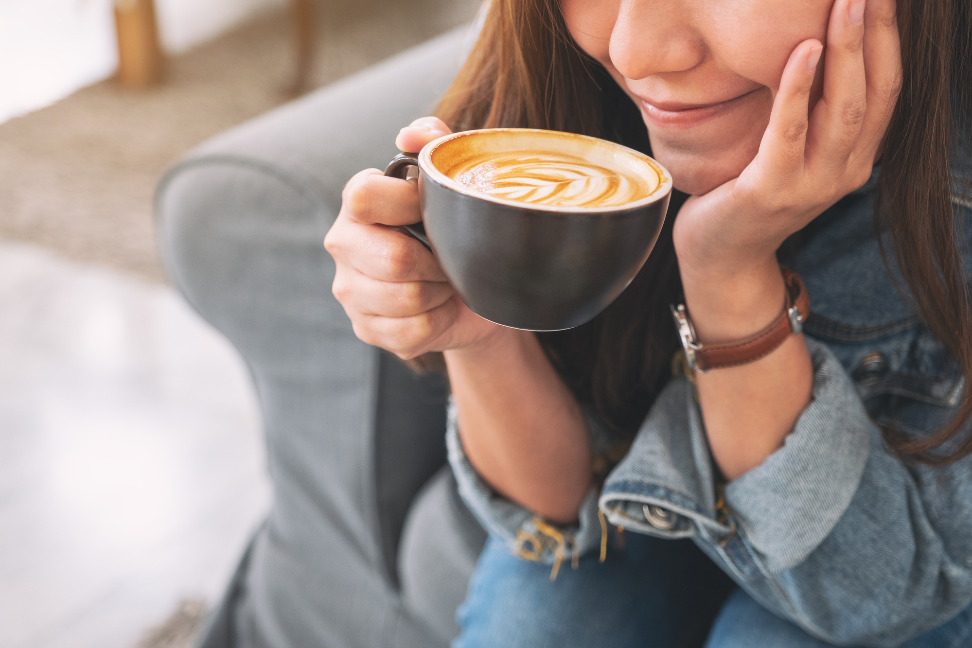 Woman sitting on a couch, sipping her coffee